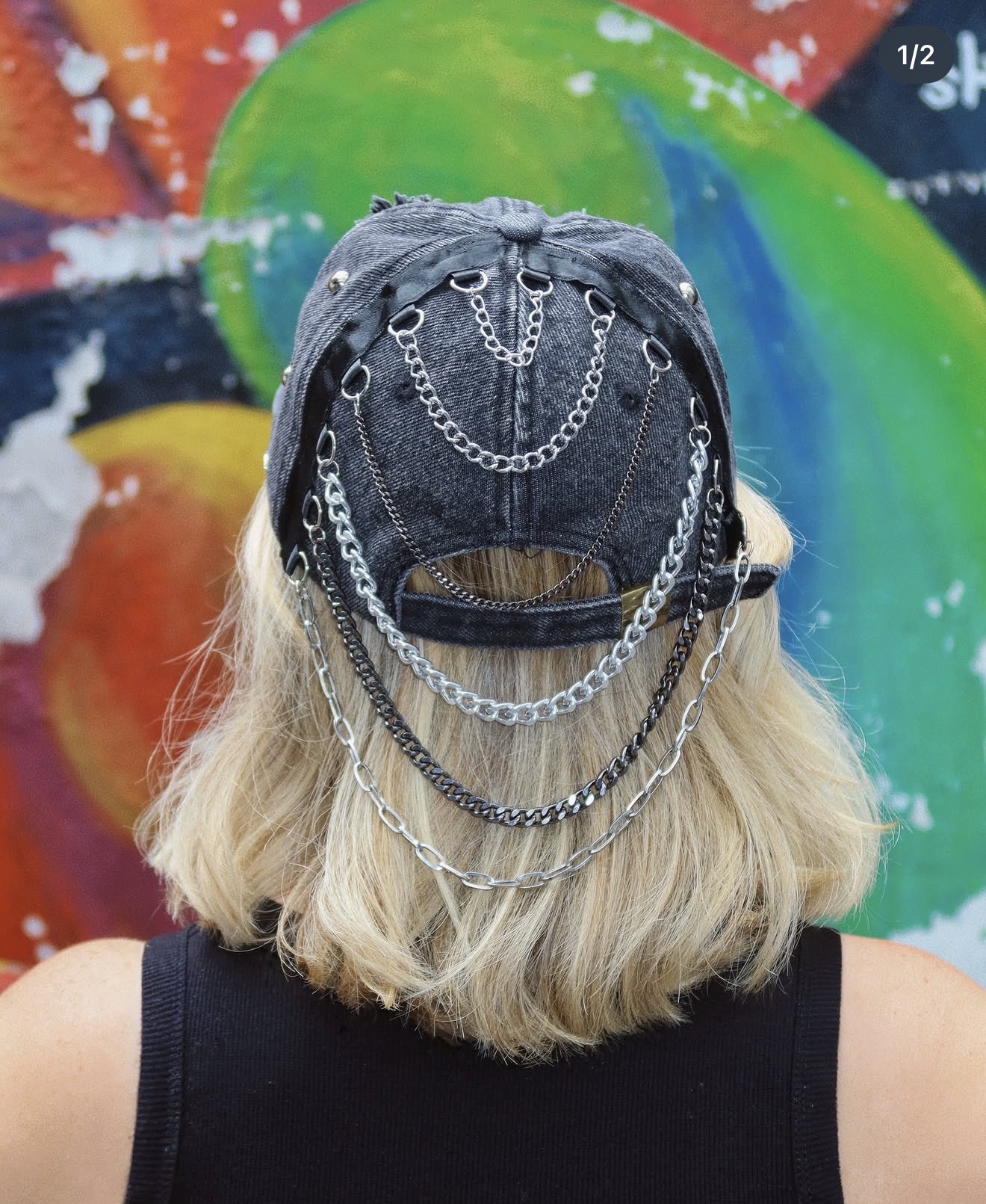 Casquette denim noire ornée de chaînes, portée devant un mur coloré